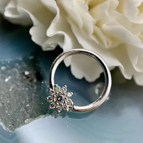 silver jewelry on display with white flower